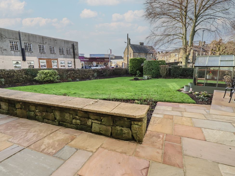 A garden with grass and a greenhouse at Linn Cottage in Hexham