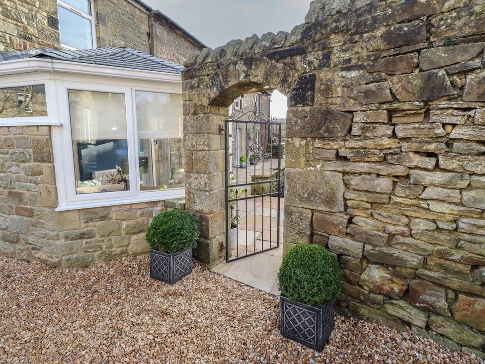 A garden with a stone wall and a gate at Linn Cottage in Hexham