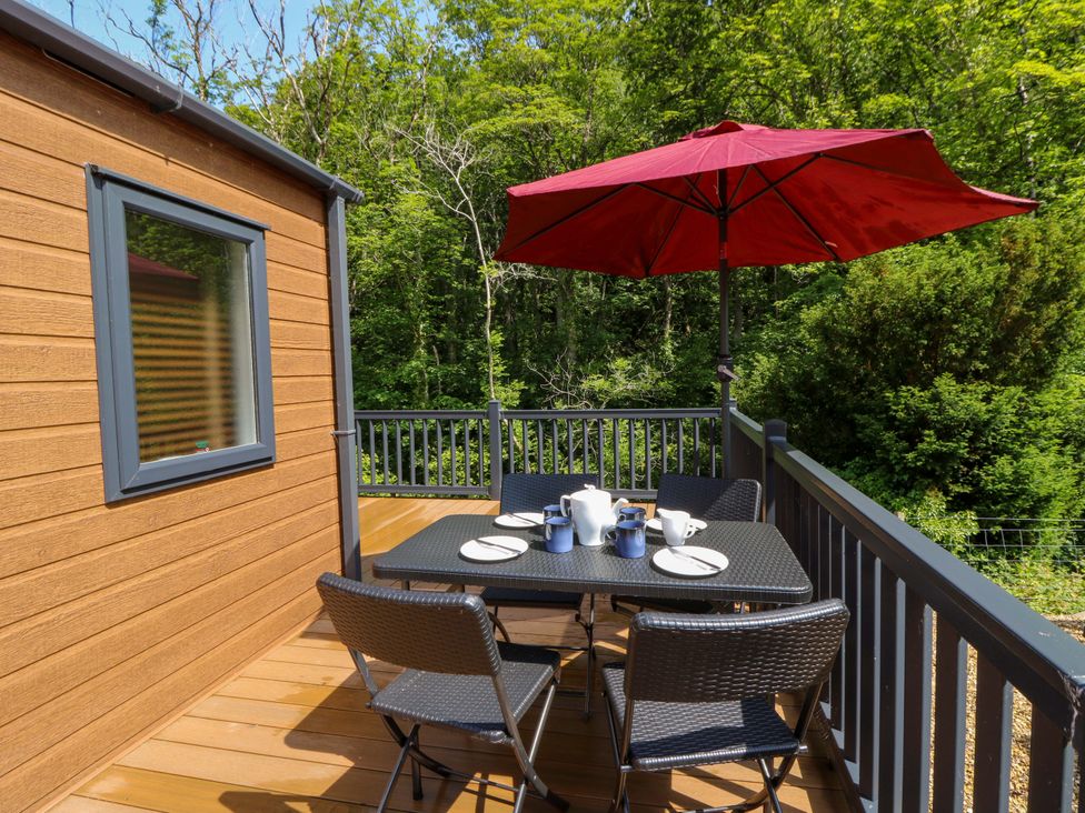 A deck with a table and chairs under an umbrella at The Beaumont No 34 in New Quay