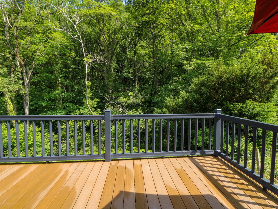 A deck with wooden flooring overlooking trees at The Beaumont No 34 in New Quay