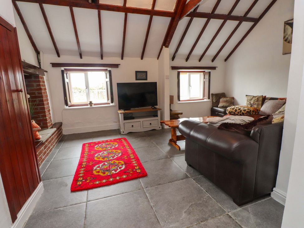 A living room with a sofa and television at 2 Llainwen Ty Croes