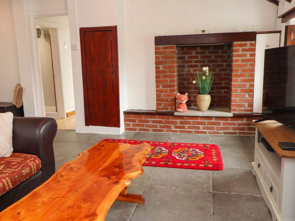 A living room with a coffee table and television at 2 Llainwen in Ty Croes
