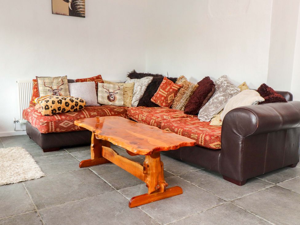 A living room with a sofa and coffee table at 2 Llainwen Ty Croes