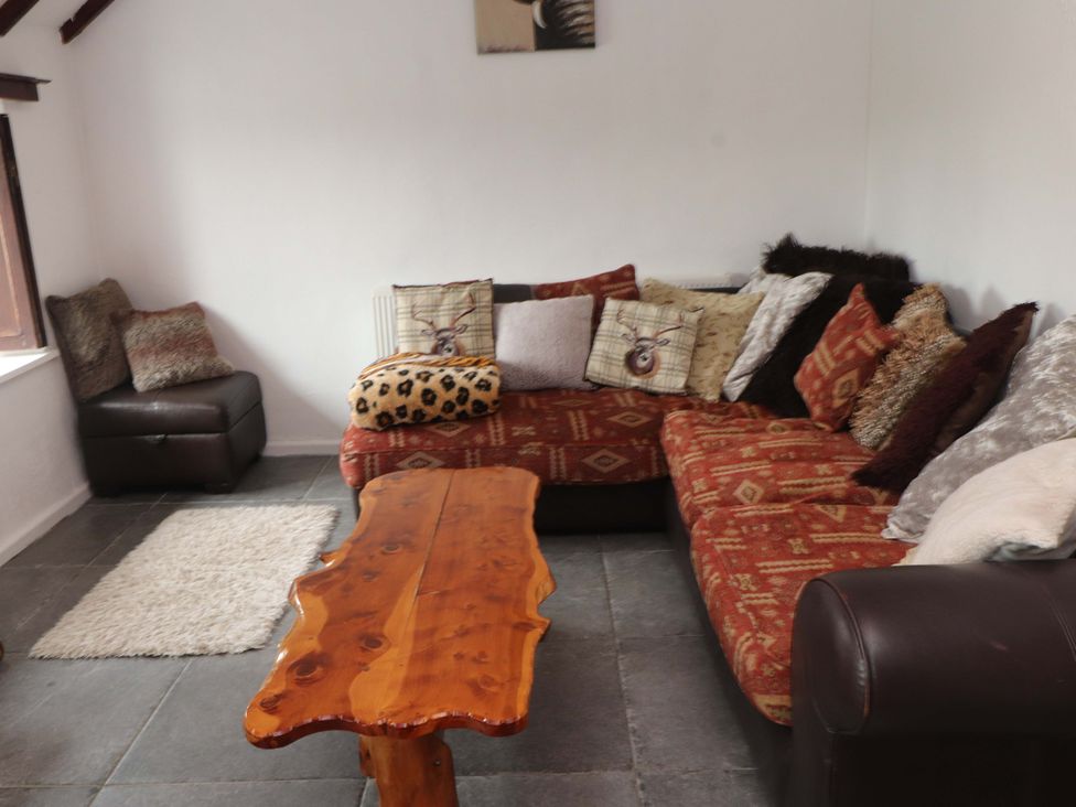 A living room with a sofa and coffee table at 2 Llainwen in Ty Croes