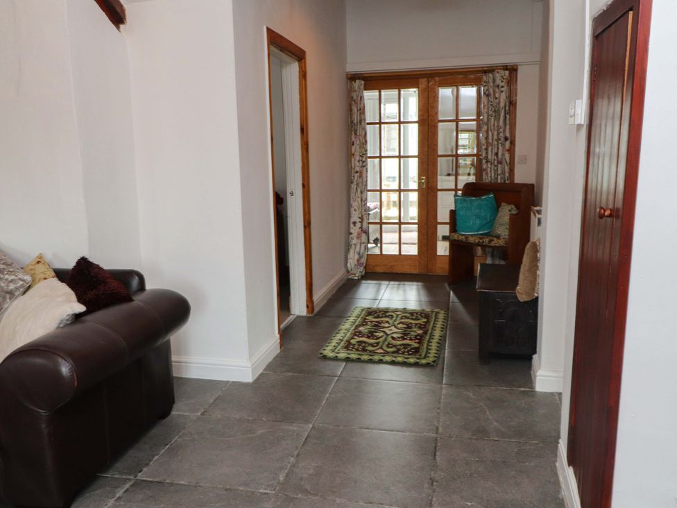A hallway with a sofa and a door leading to another room at 2 Llainwen Ty Croes