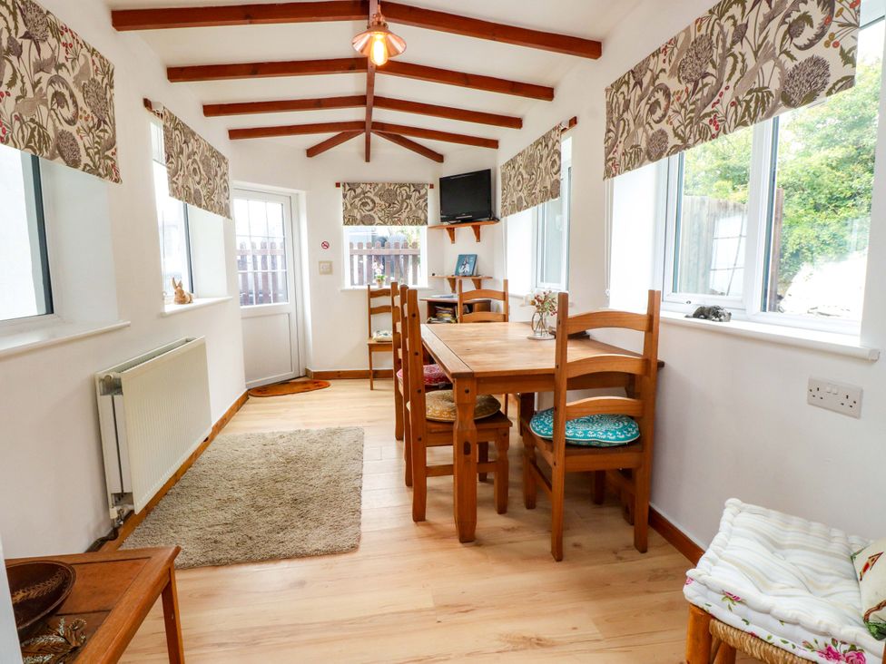 A dining room with a table and chairs at 2 Llainwen in Ty Croes
