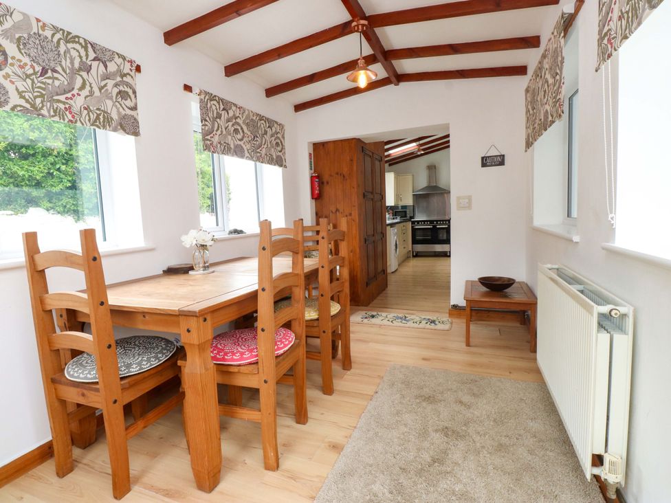 A dining room with a table and chairs at 2 Llainwen Ty Croes