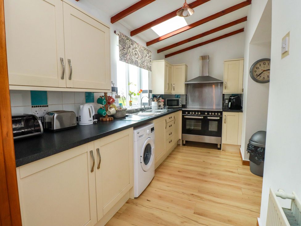 A kitchen with appliances and cabinets at 2 Llainwen Ty Croes