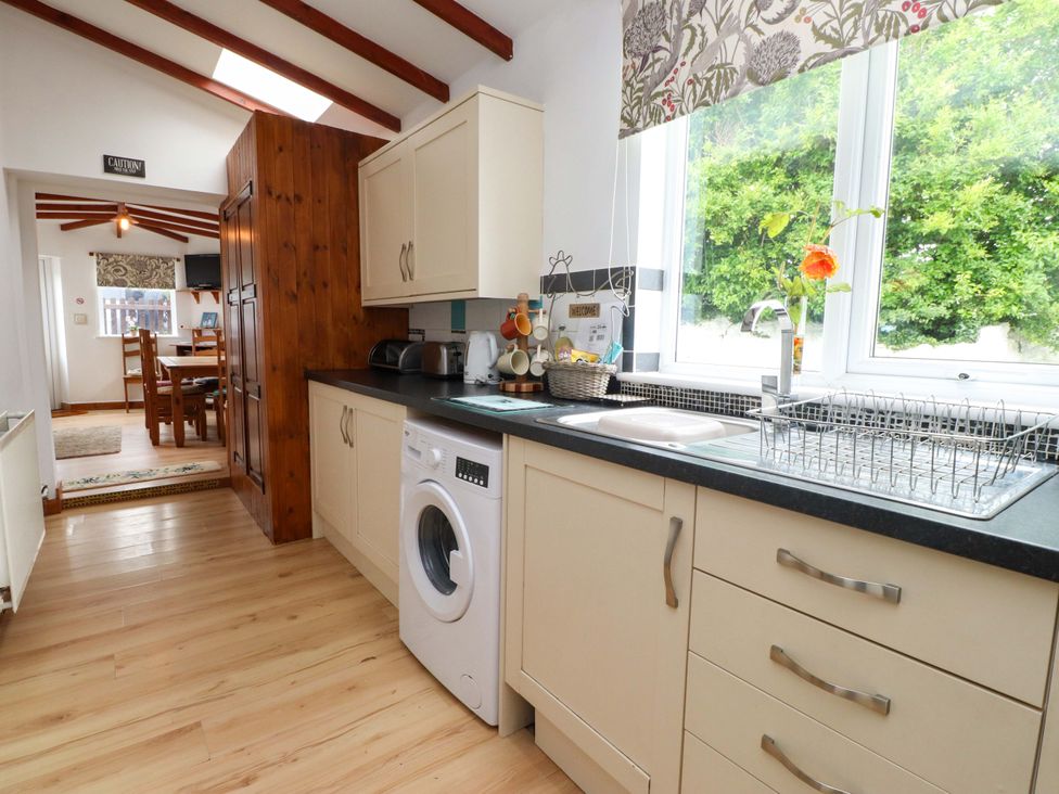 A kitchen with sink and washing machine at 2 Llainwen Ty Croes