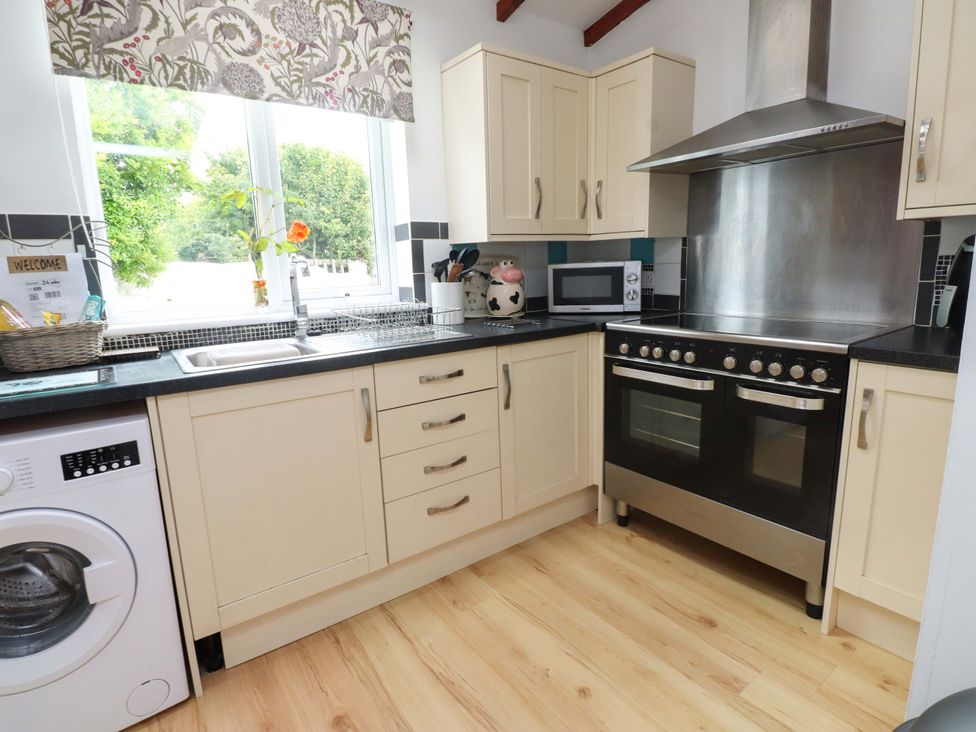 A kitchen with sink, oven, microwave and washing machine at 2 Llainwen in Ty Croes