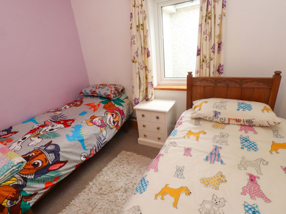 A bedroom with two beds and a bedside table at 2 Llainwen in Ty Croes
