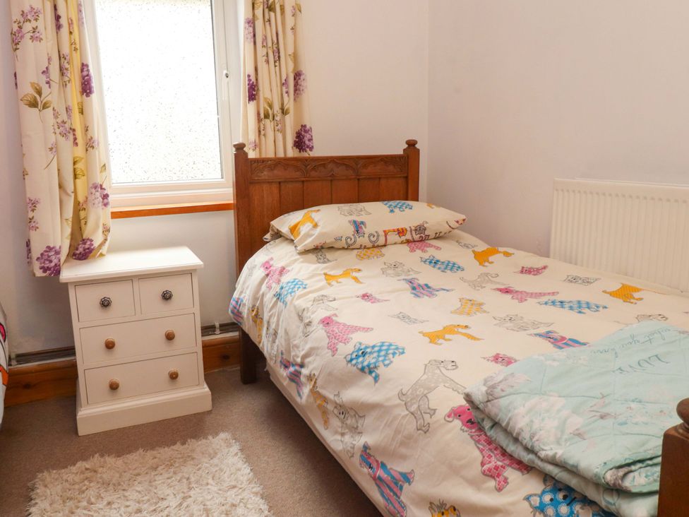 A bedroom with a single bed and a bedside table at 2 Llainwen in Ty Croes