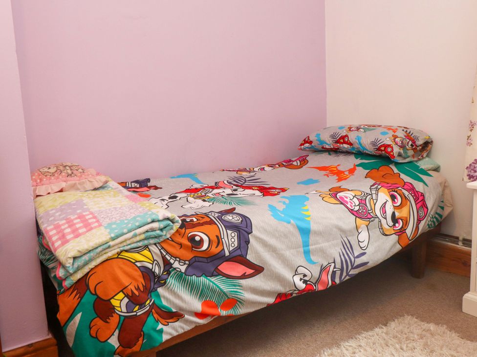 A bed with a character-themed bed sheet and pillows at 2 Llainwen Ty Croes
