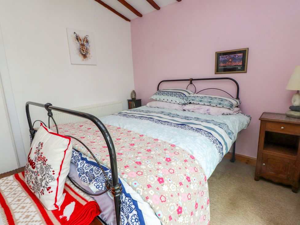 A bedroom with a bed and nightstand at 2 Llainwen Ty Croes