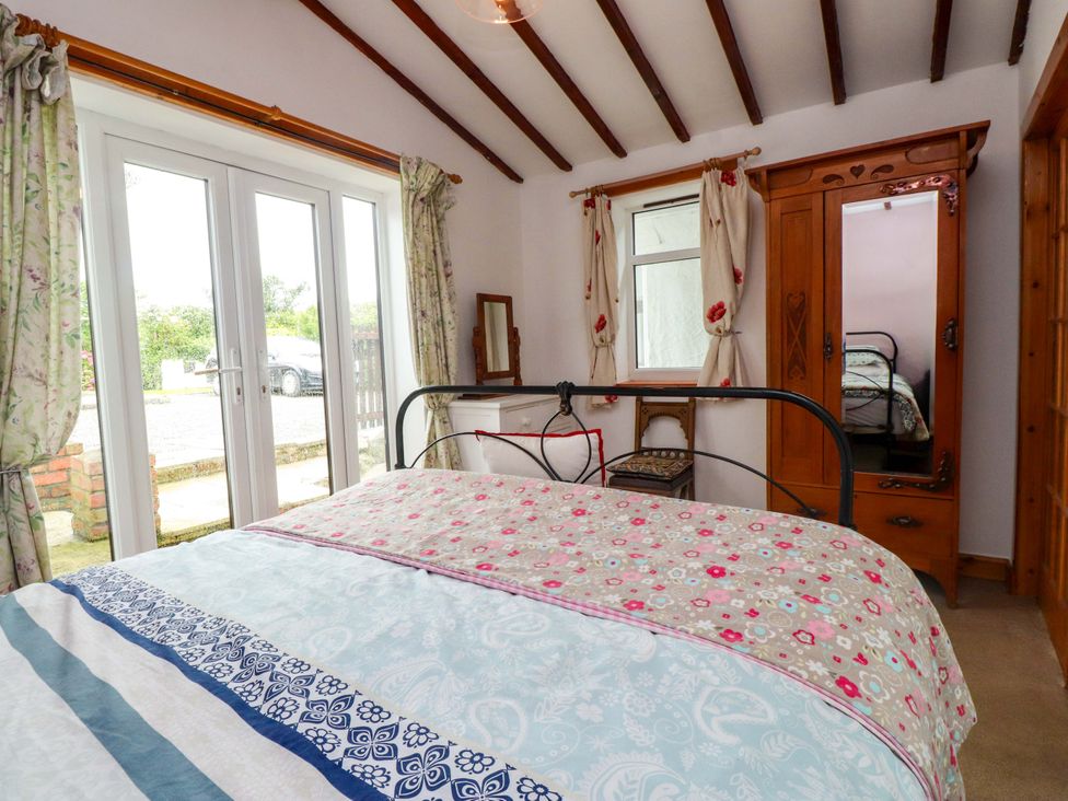 A bedroom with a bed and wardrobe at 2 Llainwen Ty Croes