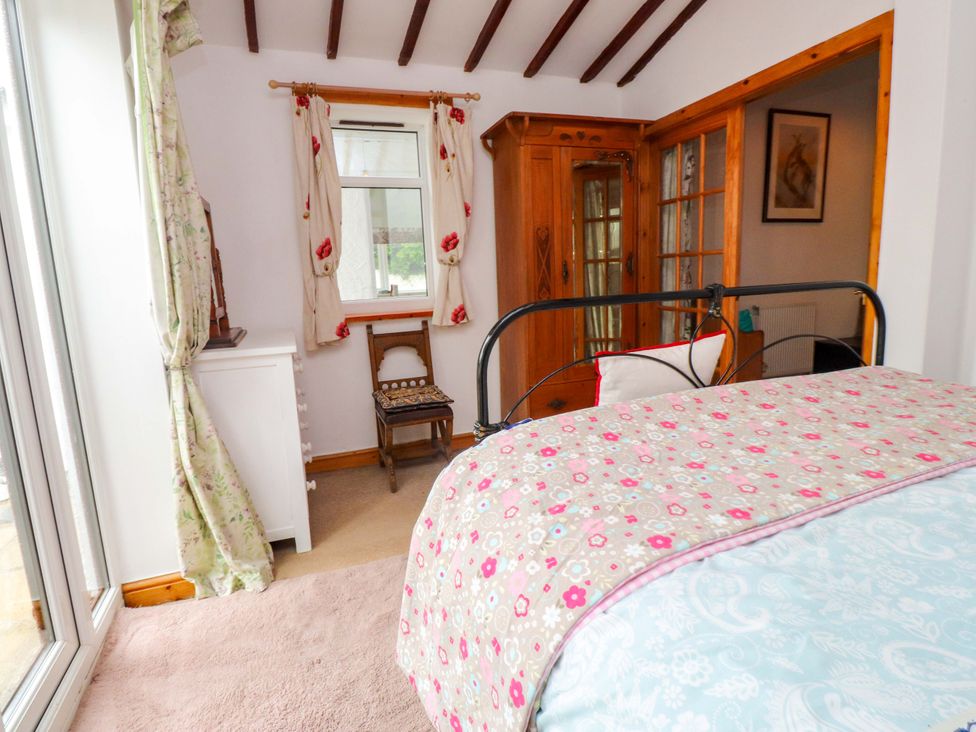 A bedroom with a bed and a wooden wardrobe at 2 Llainwen in Ty Croes