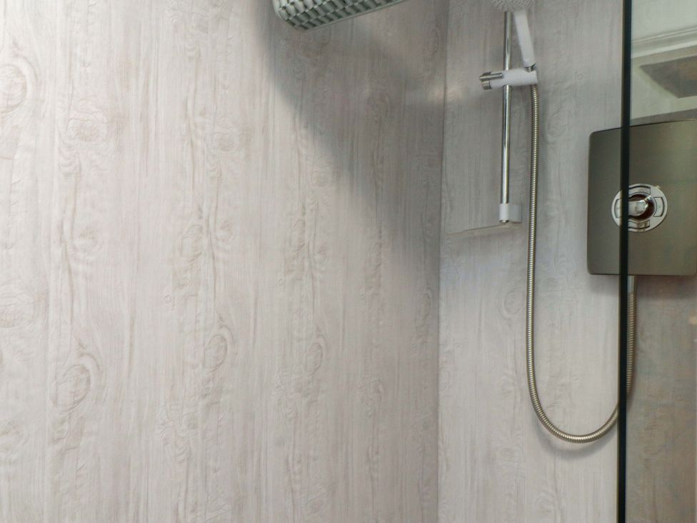 A shower with a glass panel and wall at 2 Llainwen Ty Croes