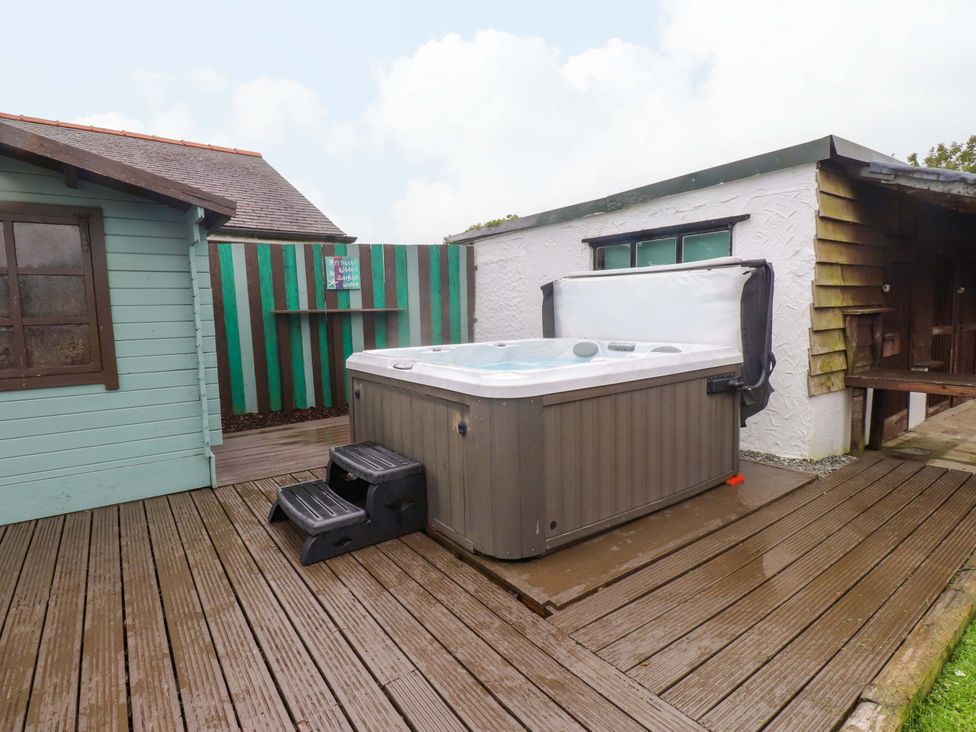 A hot tub with steps on a wooden deck at 2 Llainwen Ty Croes