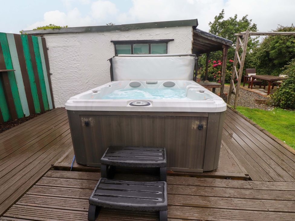 A hot tub with steps on a wooden deck in an outdoor area at 2 Llainwen in Ty Croes