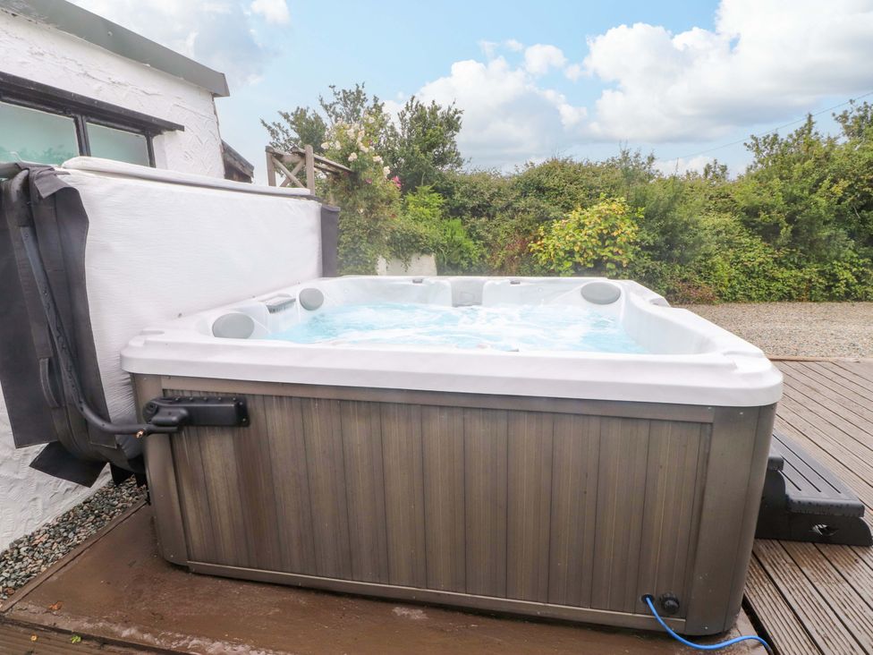 A hot tub with water on a deck at 2 Llainwen in Ty Croes