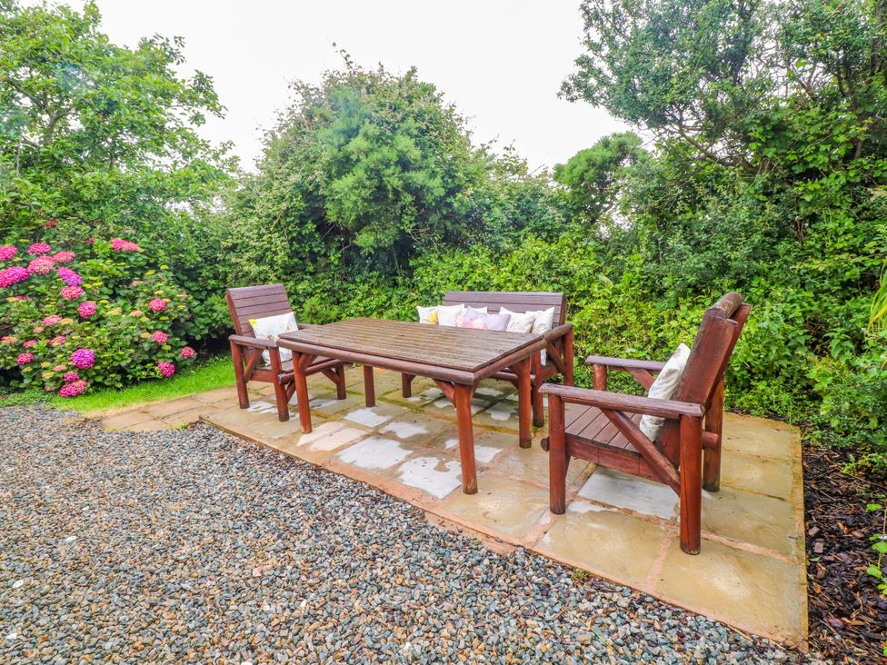 A garden with a wooden table and chairs at 2 Llainwen Ty Croes