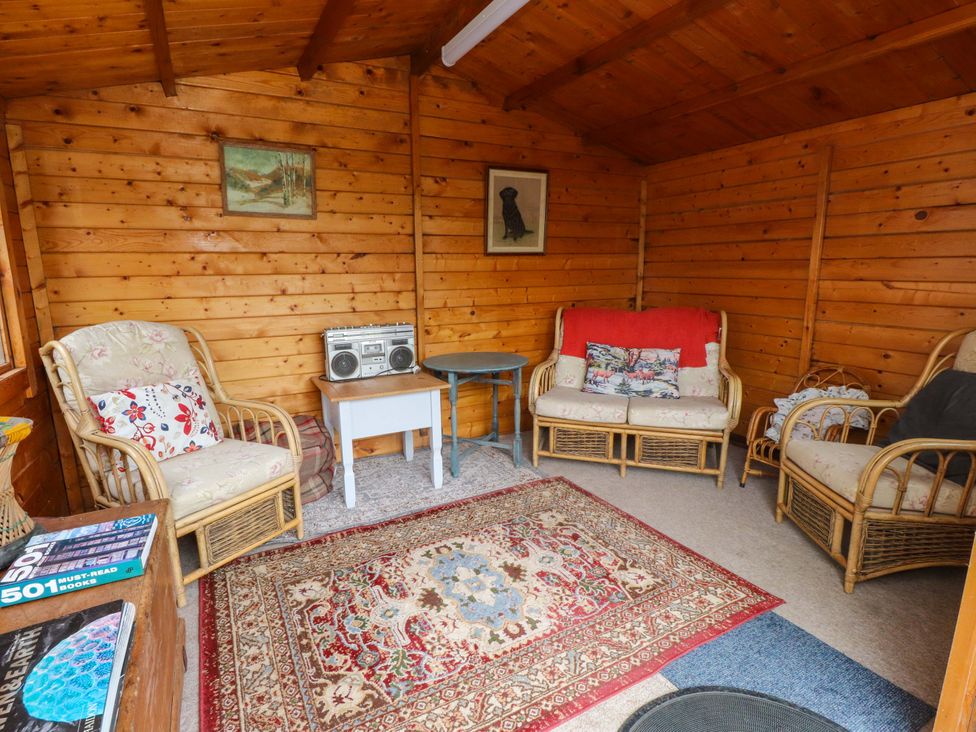 A snug with sofas, a table, and a boombox at 2 Llainwen Ty Croes
