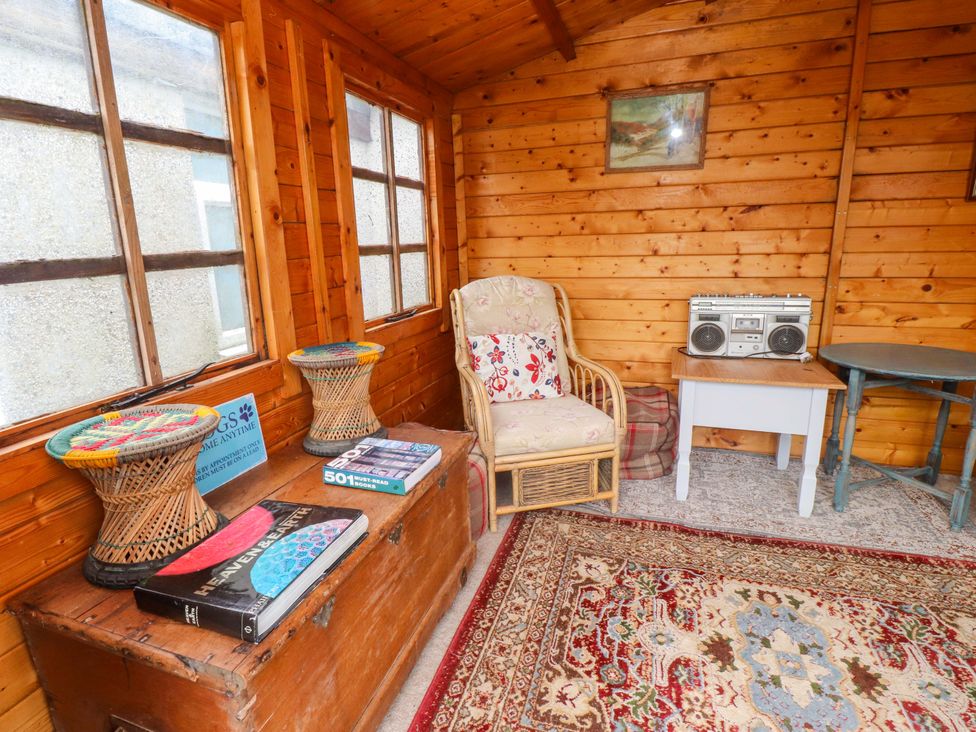 A snug with a chair, table, chest, and boombox at 2 Llainwen Ty Croes