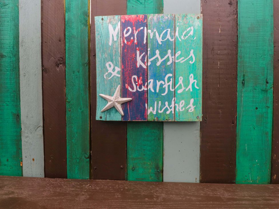 A wooden sign with a starfish on colorfully painted wood panels at 2 Llainwen Ty Croes