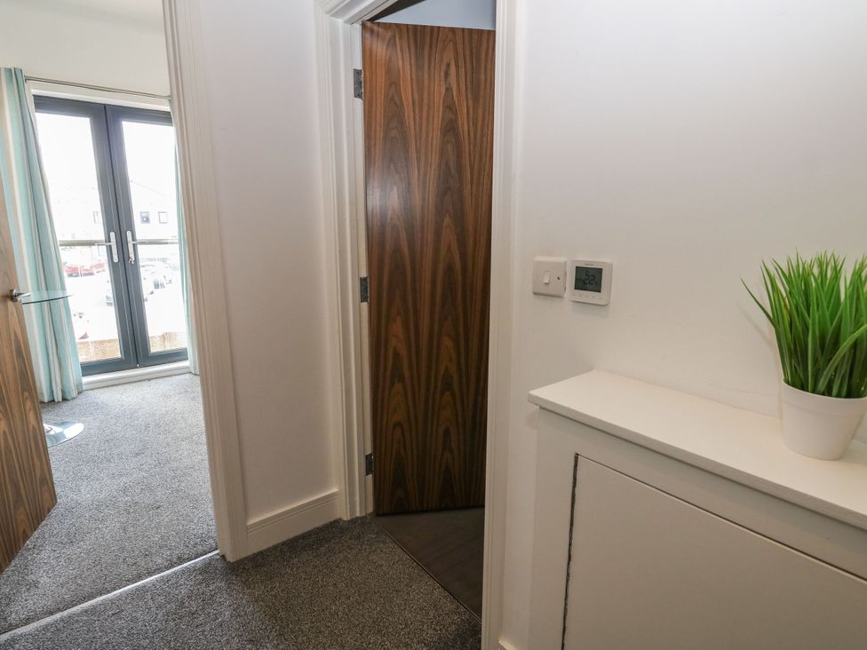 A hallway with a door and thermostat at Harbour View in Whitehaven