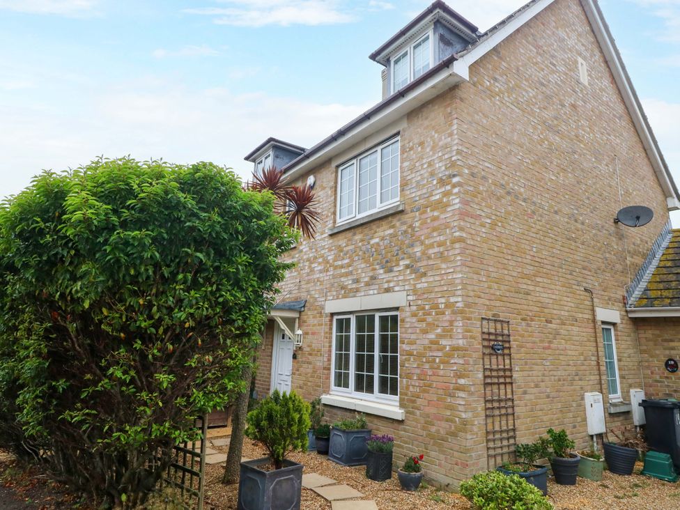 An outdoor view of a house with plants and a pathway at Fairways House in Weymouth