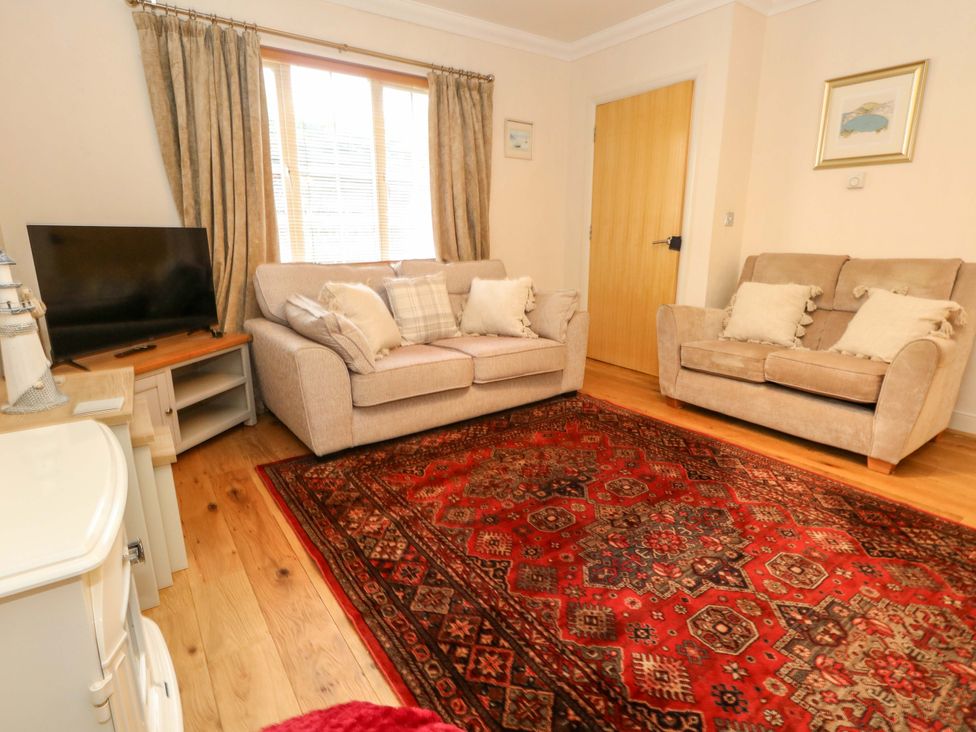 A living room with a television and two sofas at Fairways House in Weymouth