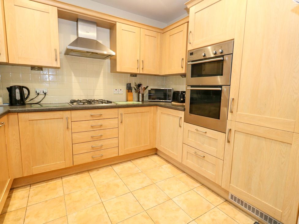 A kitchen with cabinets, hob, oven and appliances at Fairways House in Weymouth