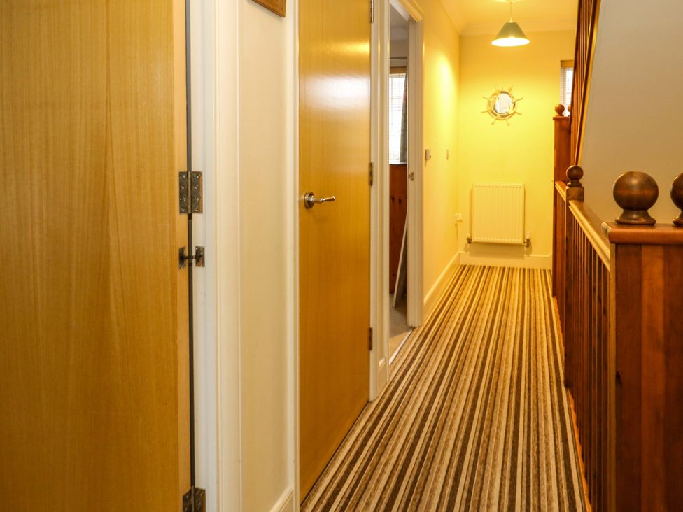 A hallway with wooden doors and a handrail at Fairways House in Weymouth