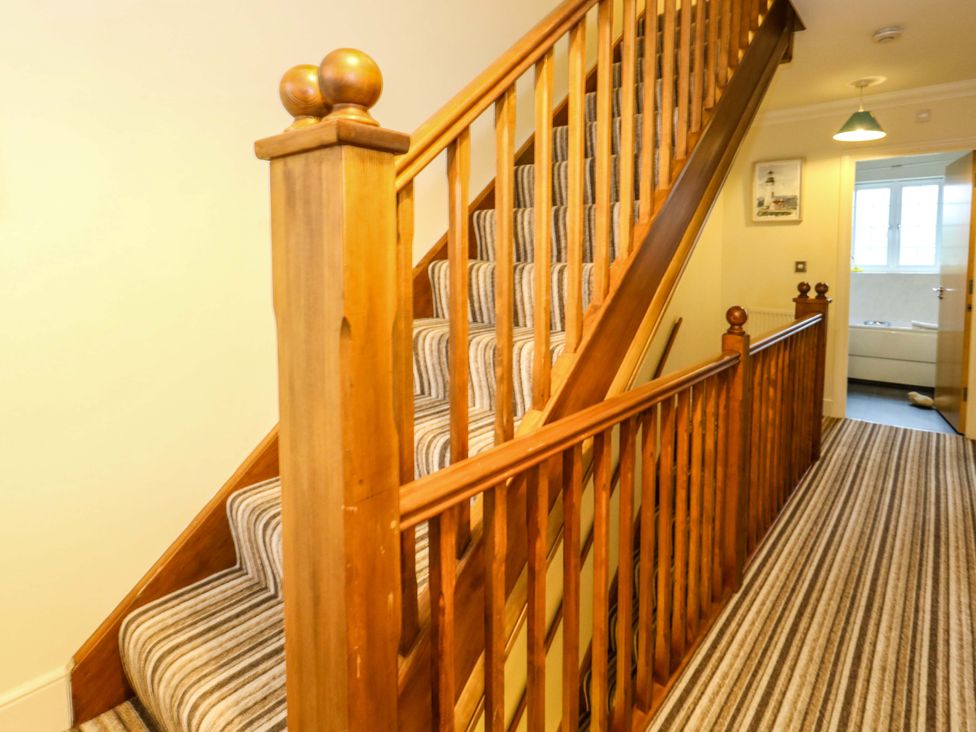 A staircase with wooden handrail in a hallway at Fairways House Weymouth