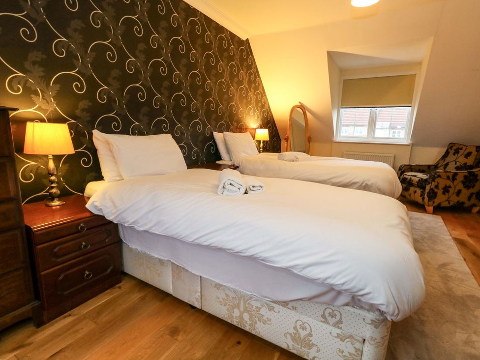 A bedroom with two beds and a lamp at Fairways House in Weymouth