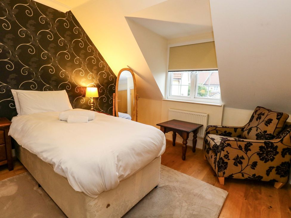 A bedroom with a bed, lamp, mirror, and table at Fairways House Weymouth