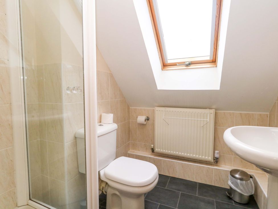 A bathroom with a shower, toilet, and sink at Fairways House, Weymouth