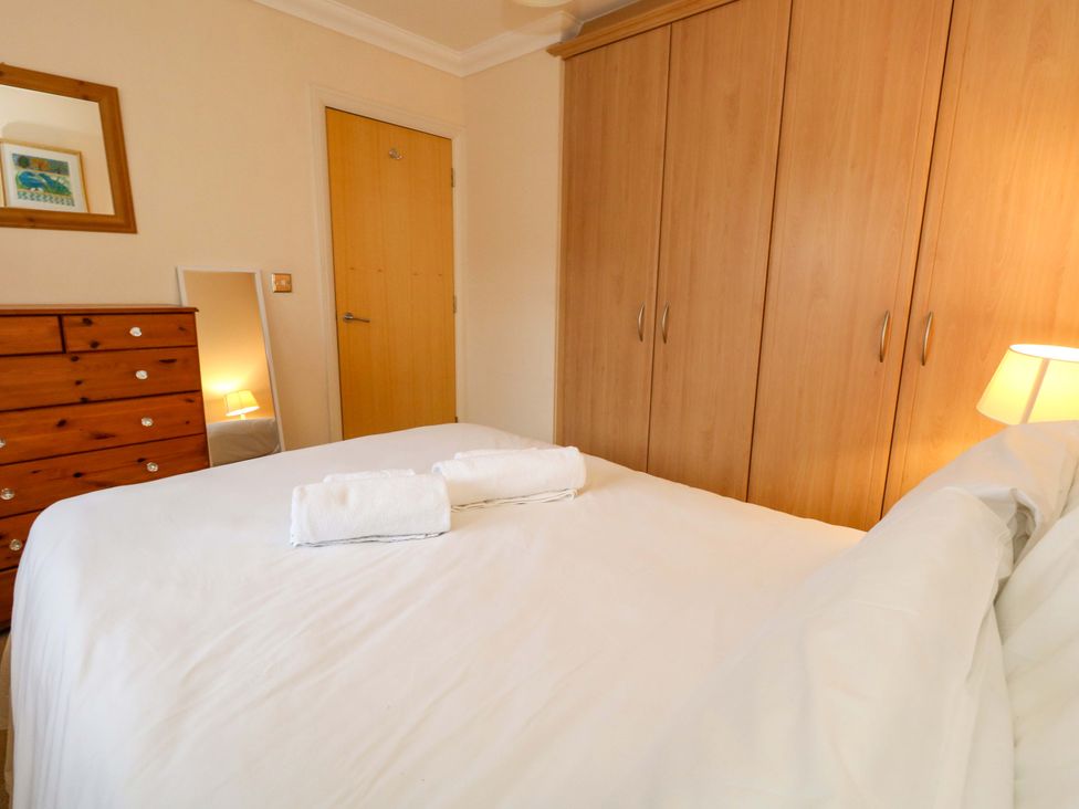 A bedroom with a bed and a wardrobe at Fairways House in Weymouth