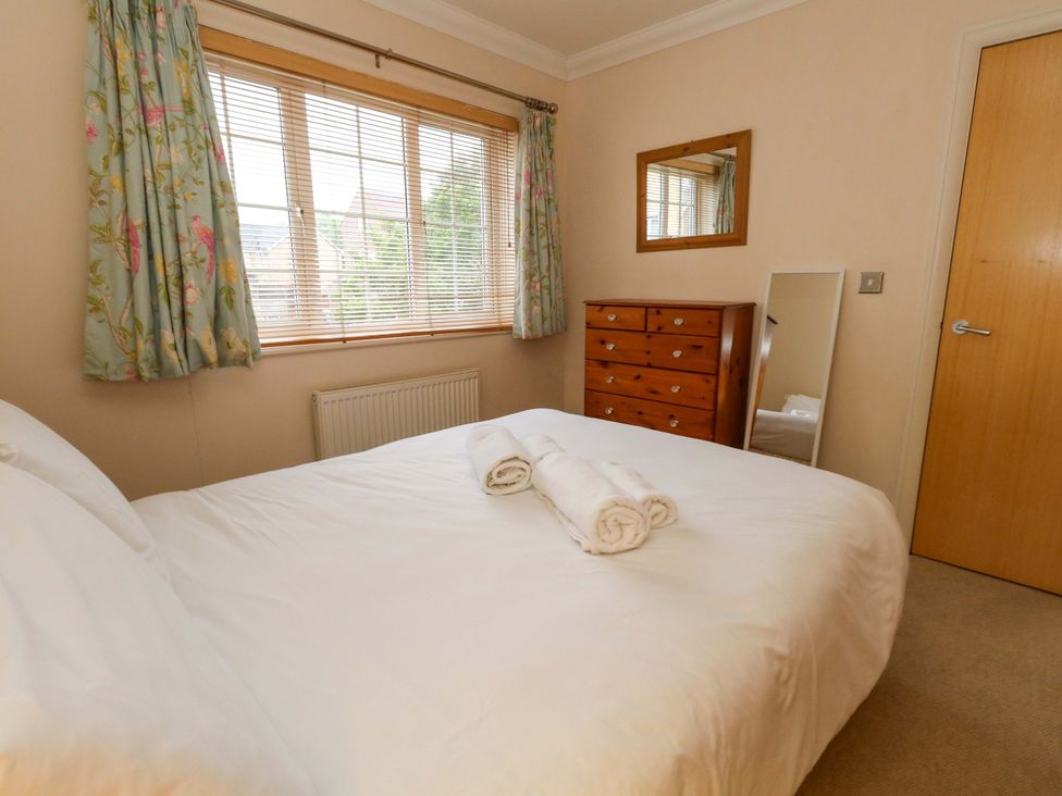 A bedroom with a bed and dresser at Fairways House in Weymouth