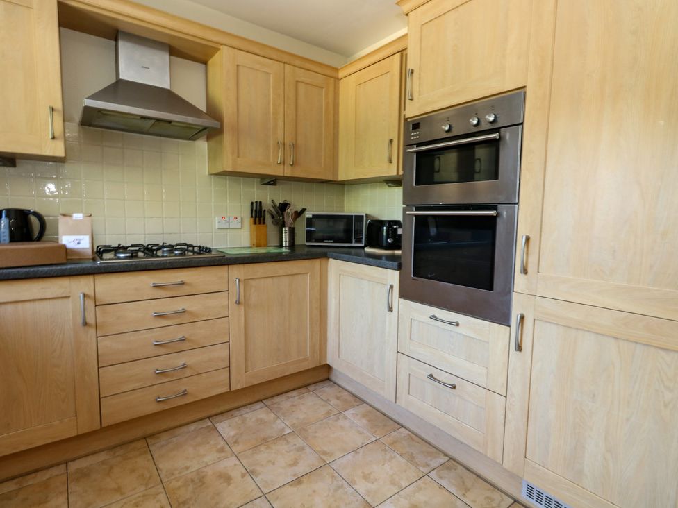 A kitchen with cabinets, oven, microwave, and kettle at Fairways House in Weymouth