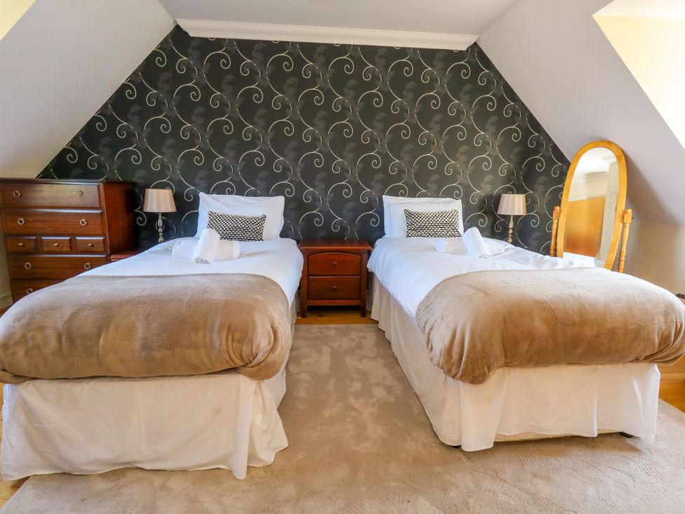 A bedroom with two beds and wooden furniture at Fairways House in Weymouth