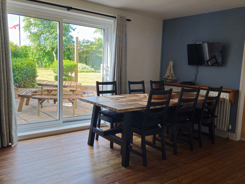 A dining room with a table and chairs visible through a sliding door at The Warren in Seahouses
