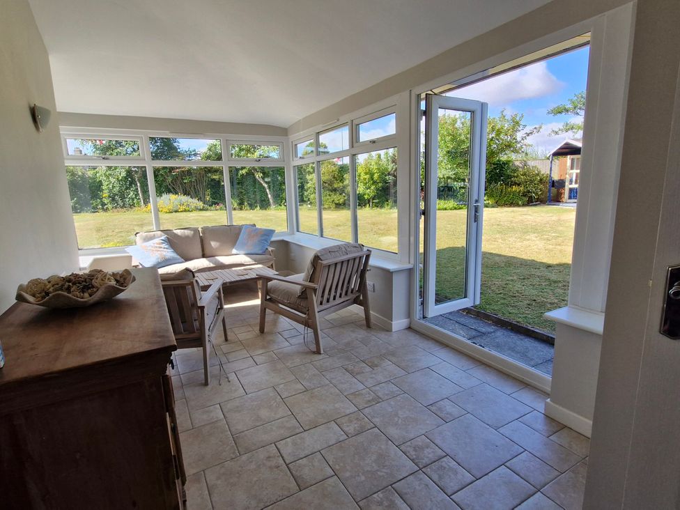 A conservatory with seating and a view of the garden at The Warren in Seahouses