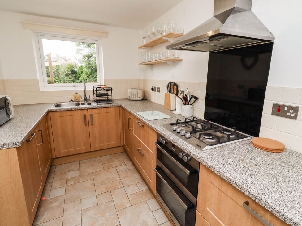 A kitchen with cabinets, sink, stove, oven, and microwave at Bari House in Seahouses
