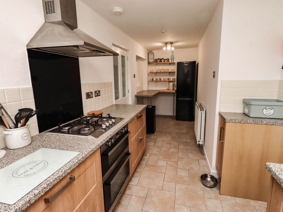 A kitchen with stove, refrigerator and shelves at Bari House in Seahouses