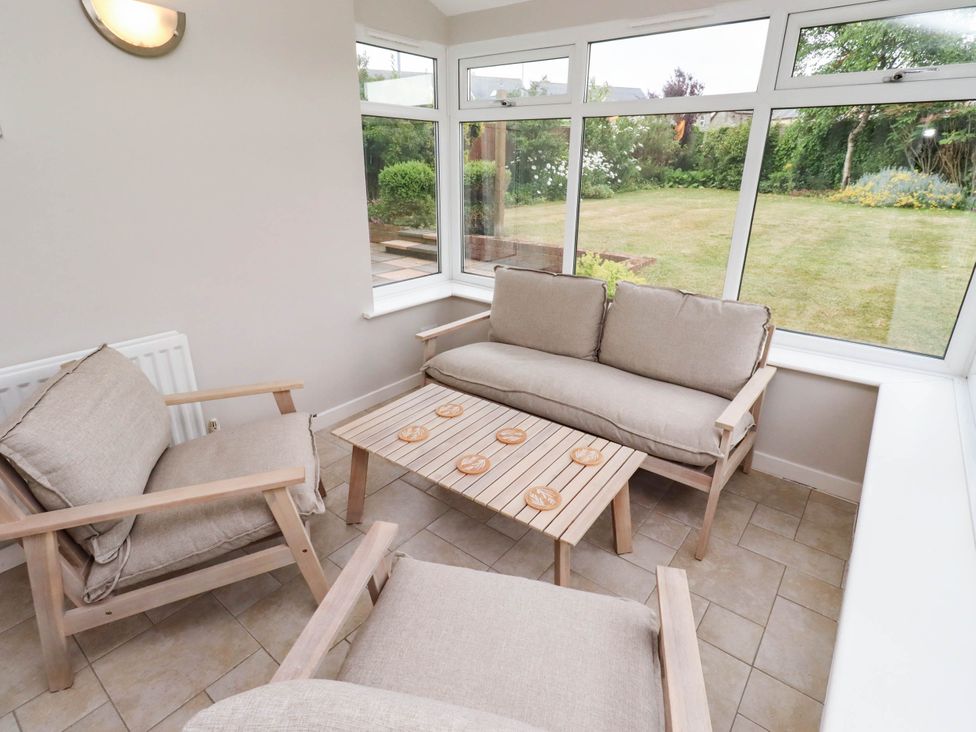 A conservatory with seating and a view of the garden at Bari House in Seahouses