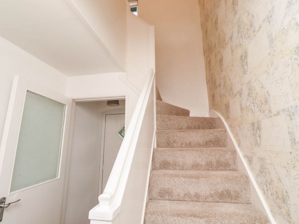 A staircase with carpet and wall design at Bari House in Seahouses