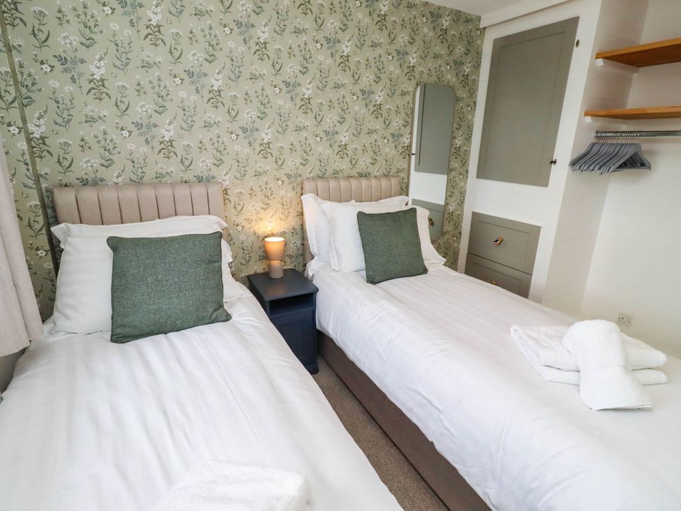 A bedroom with two single beds and a bedside table at Bari House in Seahouses