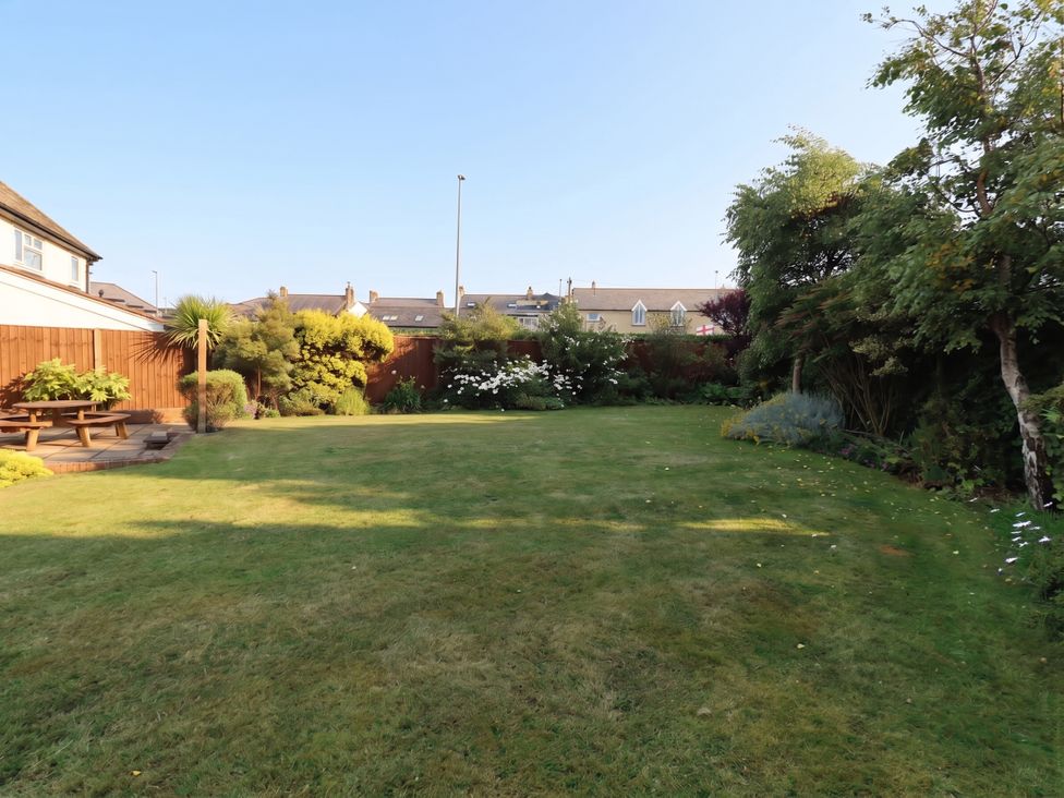 A garden with lawn, trees, and a picnic table at Bari House in Seahouses