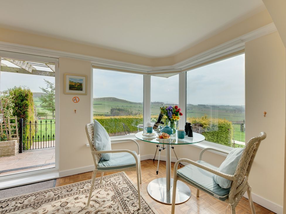 A conservatory with a table and chairs overlooking the garden at The Granary in Alnwick